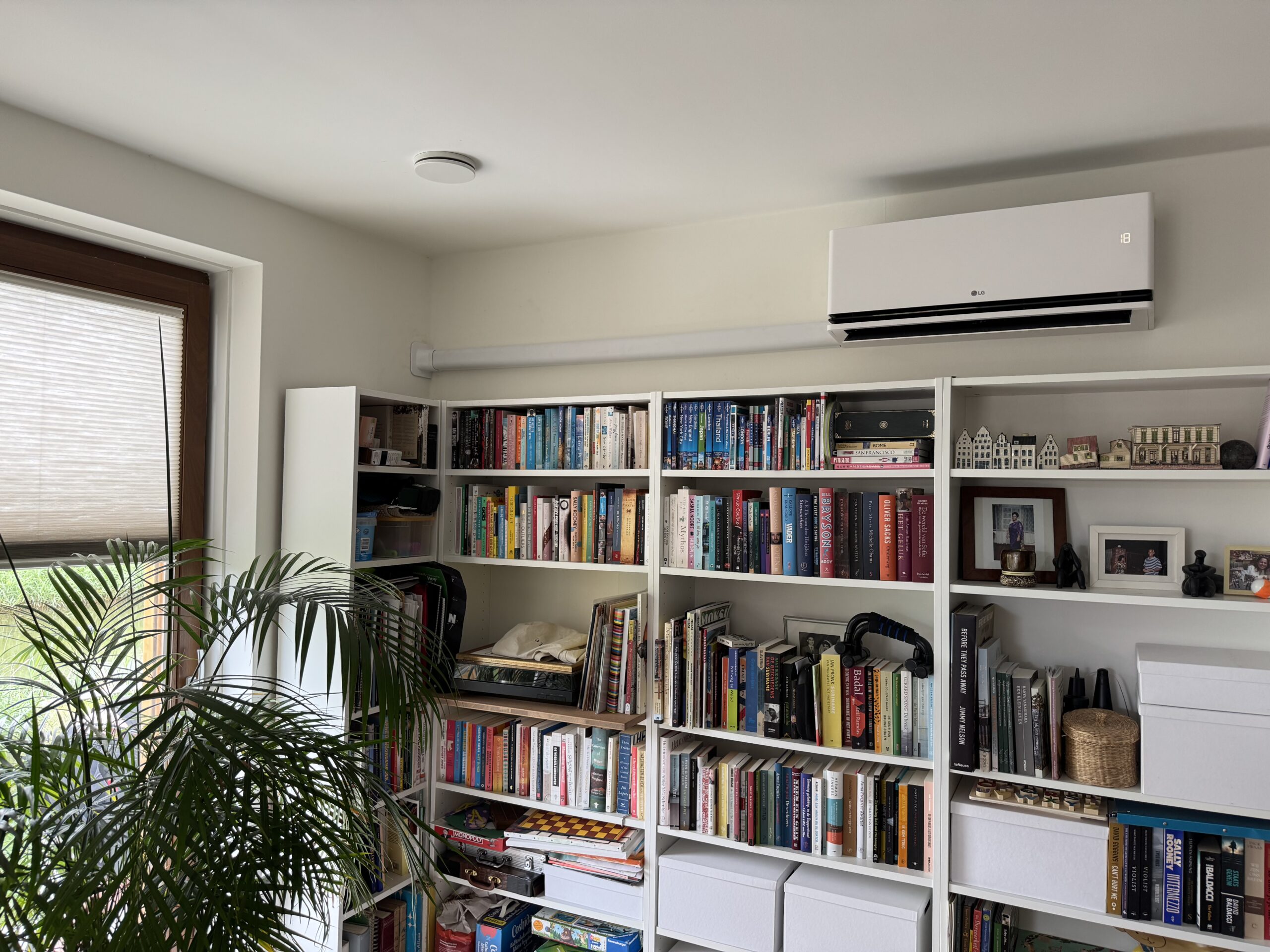Witte LG airco-binnenunit boven een boekenkast in de woonkamer