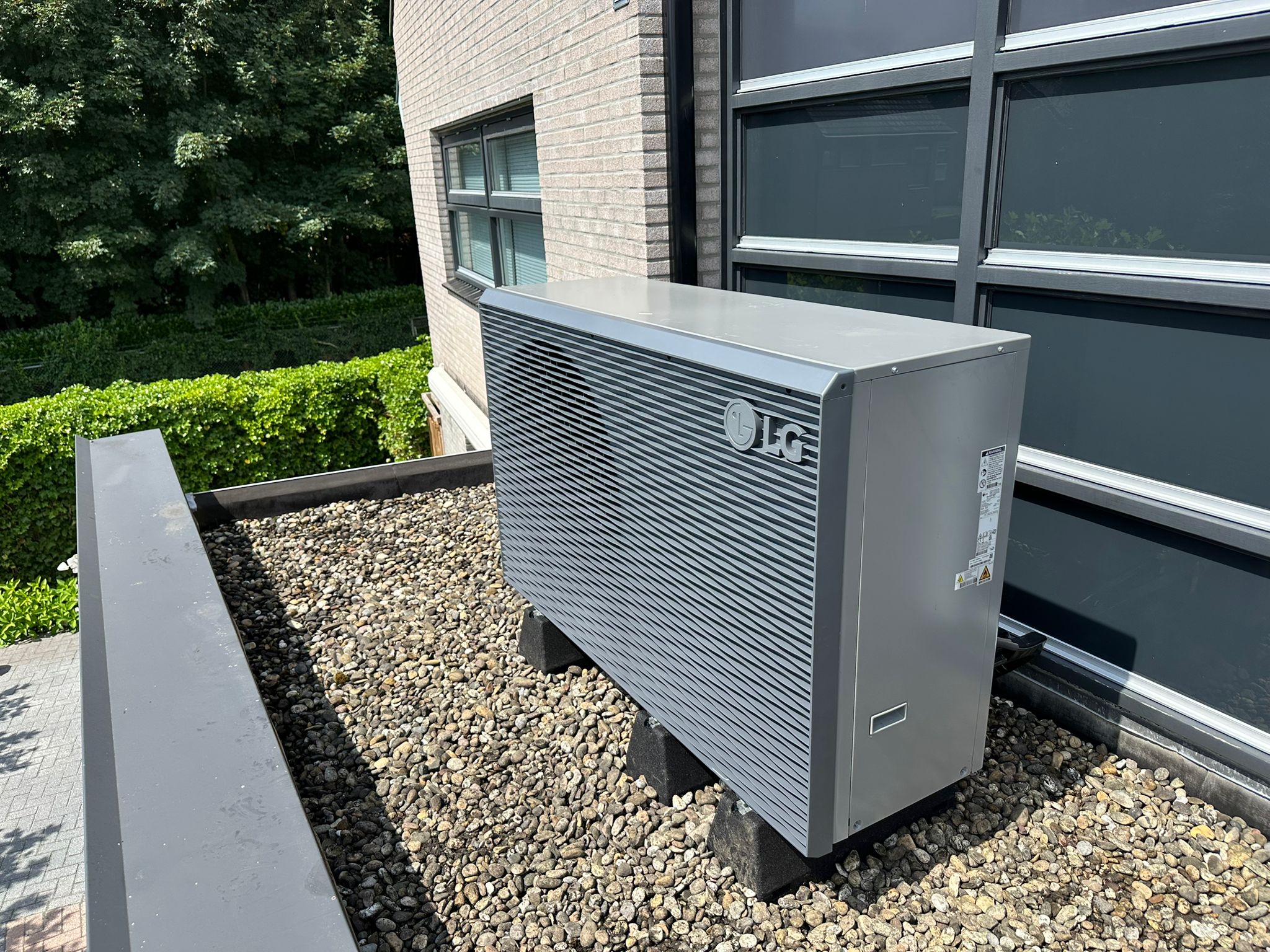 LG warmtepomp geïnstalleerd in de tuin tegen een gevel